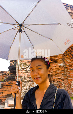 Jeune femme de la région, environ 25, promenades à l'ombre parasol à Wat Mahathat, près d'Ayutthaya, Bangkok, Thaïlande Banque D'Images