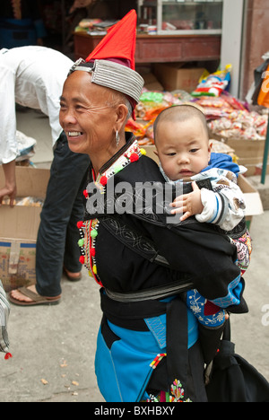 L'Asie, Chine, Yunnan, Honghe Préfecture, Jinping. Tête rouge Yao femme avec bébé en sac à dos. Banque D'Images