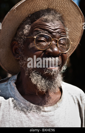 Vieil homme avec chapeau de paille et lunettes à la à l'appareil photo, Chinotimba, le Zimbabwe, l'Afrique. Banque D'Images