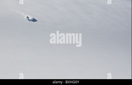 Le dirigeant d'une planche d'un virage sur un large champ de neige vide, à La Grave, France Banque D'Images