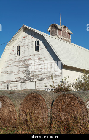 Ancienne grange blanche avec des bottes de foin dans l'Iowa. Banque D'Images