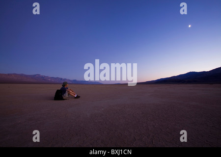 Homme est assis sur le lit du lac à sec de lune - Death Valley, California, USA Banque D'Images