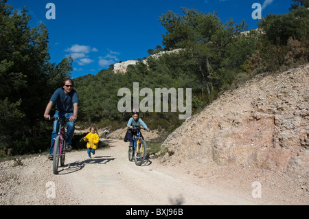 Route de terre le long des promenades en père en vtt avec son fils alors que sa fille s'exécute avec eux, Vitrolles, Aix en Provence, France Banque D'Images