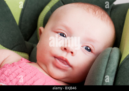 Portrait d'une fille de bébé tout-petit couché confortablement dans le siège de voiture Banque D'Images