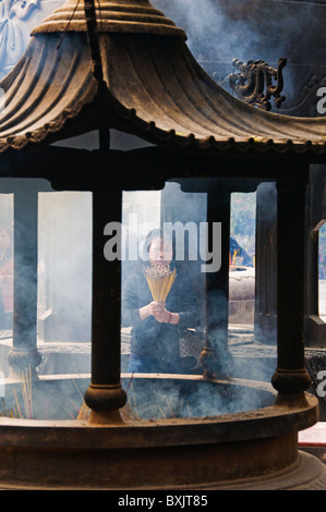 Femme Asiatique offrant de l'encens au temple bouddhiste à Hong Kong, Chine Banque D'Images