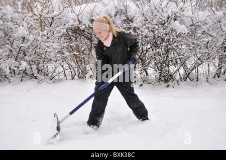 Yong girl pelleter la neige. Banque D'Images