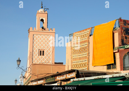 Minaret de la mosquée et les tapis drapé sur toit-terrasse de la place Djemaa el-Fna à Marrakech Lieu de rencontre Banque D'Images