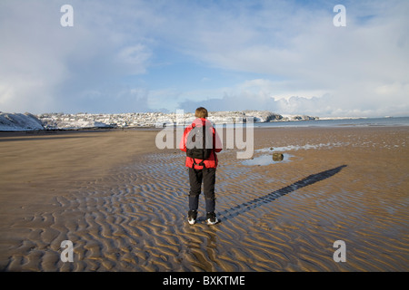 Benllech Isle of Anglesey au nord du Pays de Galles UK Décembre femme marchant le long de la plage pavillon bleu sur une belle journée seul hivers sur plage déserte hors saison Banque D'Images