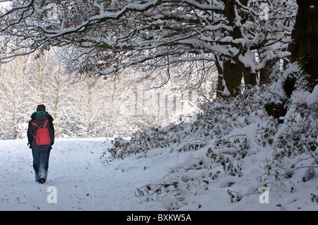 Femme marche le long d'un chemin couvert de neige à Redditch, Worcestershire. Banque D'Images