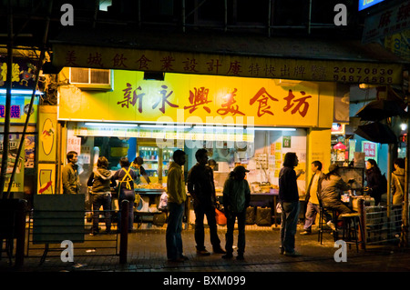 Les jeunes gens oriental debout sur coin de rue, entreposage extérieur au centre-ville de Hong Kong, Chine Banque D'Images