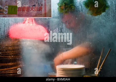 Asian man preparing food at outdoor stall on city street dans le centre-ville de Hong Kong, Chine Banque D'Images