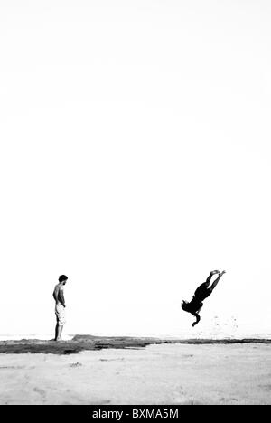 Les jeunes hommes la pratique de sauts acrobatiques sur la plage, de la baie tokomaru, nouvelle-zélande Banque D'Images