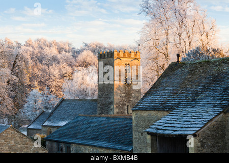 Le coucher de soleil sur l'église St Andrews dans le givre couverts village des Cotswolds de Coln Rogers, Gloucestershire Banque D'Images