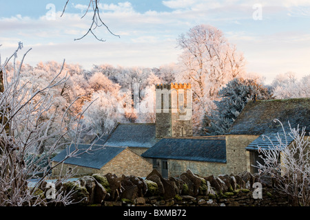 Le coucher de soleil sur l'église St Andrews dans le givre couverts village des Cotswolds de Coln Rogers dans la vallée de la Colne, Gloucestershire UK Banque D'Images