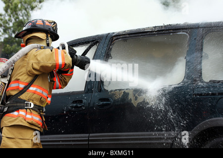 Pompier sur un hoseline combattre un incendie de voiture Banque D'Images