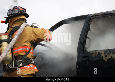 Pompier sur un hoseline combattre un incendie de voiture Banque D'Images