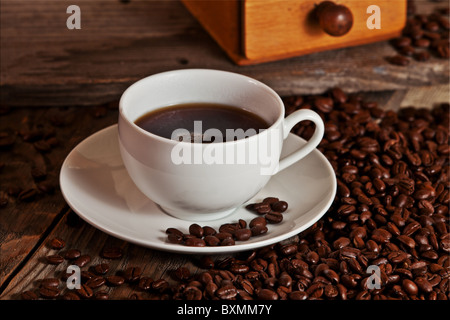 Tasse de café riche se trouve sur un monticule de haricots avec un broyeur de café dans l'arrière-plan. Prix pour copie. Banque D'Images