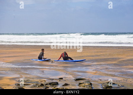 Deux surfeurs assis sur la plage de Fanore, comté de Clare, Irlande Banque D'Images