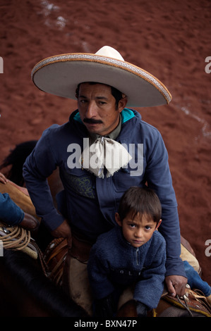 Un Charro mexicain avec son fils monte un cheval après une Charrería concurrence, ou rodeo, le sport national du Mexique, à Texcoco, Mexique Banque D'Images