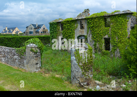 Nouveau contraste propriétés modernes à côté de vieille maison abandonnée dans le besoin de rénovation à Comté de Wexford, Irlande Banque D'Images