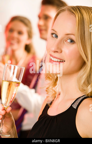 Portrait de jolie femme tenant le verre de champagne à l'arrière-plan de deux personnes Banque D'Images