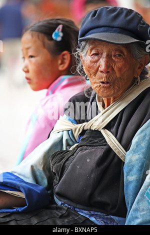 La femme Naxi s'assit à côté d'une jeune fille dans la rue, Lijiang, province du Yunnan, Chine Banque D'Images