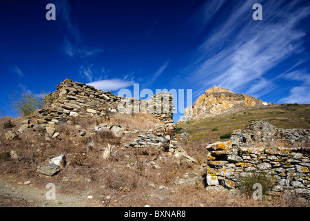 Sur l'île grecque de Tinos, Cyclades, ruines des anciens bâtiments en pierre avec Mont Exobourgo en arrière-plan. Banque D'Images