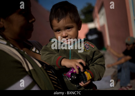 Une femme migrante d'Amérique centrale tient son fils dans ses bras dans un refuge pour migrants situé le long de la ligne de chemin de fer dans la ville de Mexico. Banque D'Images