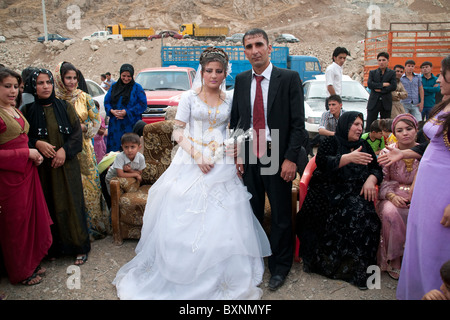 Une femme et un homme poser avec des invités à un mariage kurde en plein air dans les montagnes du nord de l'Irak, près de la ville de Rowanduz et la frontière iranienne. Banque D'Images