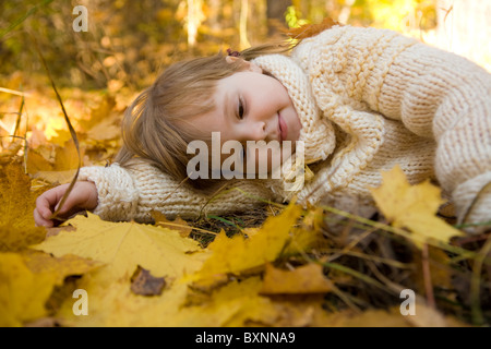 Fatigué girl relaxing on autumn sol recouvert de feuilles d'érable sec Banque D'Images