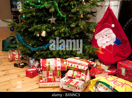 Cadeaux de Noël et bas de Noël autour de l'arbre de noël dans une maison anglaise à la veille de Noël Londres, Royaume-Uni Banque D'Images