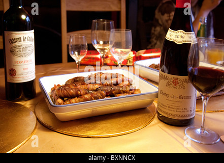 Saucisses enrobé de bacon et de bouteilles de vin rouge sur la table de dîner de Noël, UK Banque D'Images