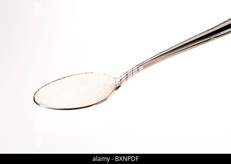 Cuillère à café de sel ou de sucre sur un fond blanc pour décoration Banque D'Images