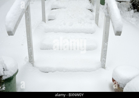 Mains courantes en bois recouvert de neige sur les étapes menant à une maison de banlieue, au Royaume-Uni. Banque D'Images