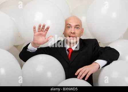 Droit de funny man in suit entouré par des ballons looking at camera Banque D'Images