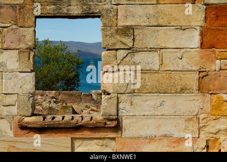 Un navire se trouve à l'ancre, vu à travers la fenêtre d'un bâtiment en ruine au Norfolk Bay historical site. Banque D'Images