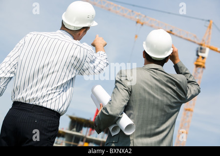 Image de deux travailleurs debout un retour et montrant à crane Banque D'Images