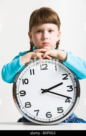 Cute little girl avec grande horloge de regarder d'une manière sérieuse Banque D'Images