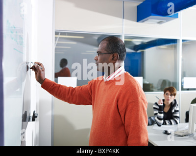 Classe d'ordinateur avec Indian male teacher writing on board et les étudiants en arrière-plan. Vue de côté, de forme horizontale, jusqu'à la taille Banque D'Images