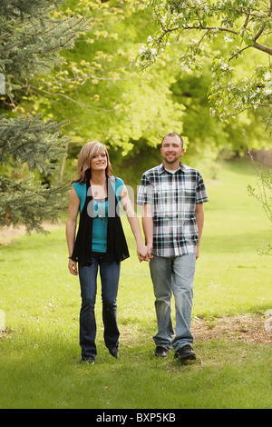 Heureux couple holding hands walking in a park Banque D'Images