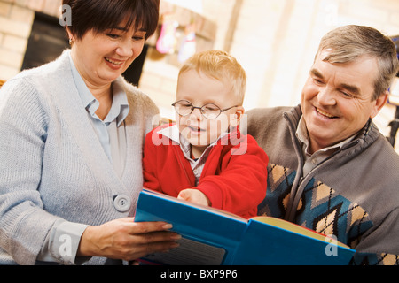 Portrait de garçon attentionné de regarder la page de livre en lecture avec ses grands-parents Banque D'Images