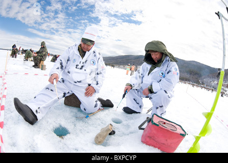 UST-Barguzin, Russie - le 11 avril : deux pêcheurs en longues robes blanches s'asseoir et de poisson à trous de glace au cours de la 5e édition de la pêche Baïkal, Apri Banque D'Images