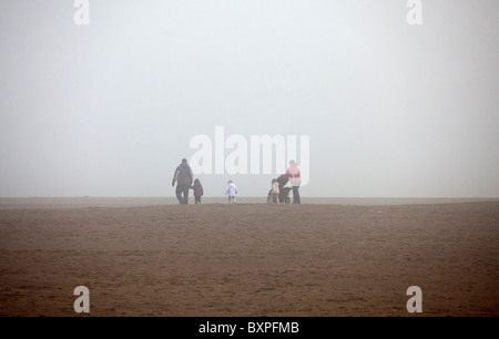 Skegness, dans le Lincolnshire, au Royaume-Uni.Skegness, dans le Lincolnshire, au Royaume-Uni. Une famille brave le brouillard sur la plage de Skegness. Banque D'Images
