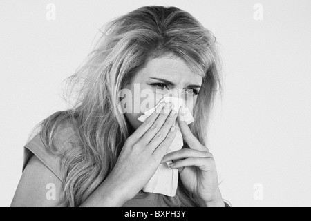 Jeune femme blonde avec un éternuement froid et s'être mouché le nez sur un tissu Banque D'Images