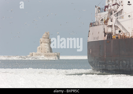 Cargo M/V Sam Laud à Cleveland Harbour en face de l'ouest du port de Cleveland couvertes de glace Pierhead Phare. Banque D'Images