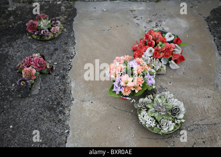 Fleurs artificielles et en céramique sur une tombe dans le cimetière de Die, en France. Banque D'Images