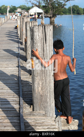 Un jeune pêcheur sur le pont en teck U Bein, qui enjambe le lac Taugthaman dans Amarapura près de Mandalay en Birmanie. Banque D'Images