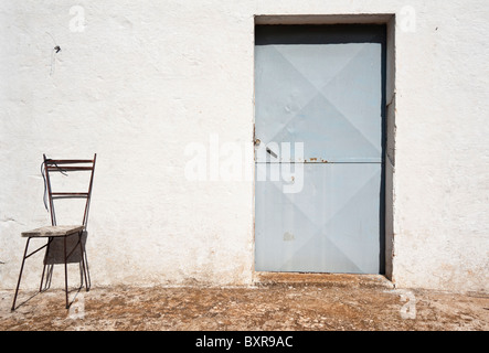 Le fer forgé chaise contre un mur blanc, Ostuni, Pouilles, Italie Banque D'Images