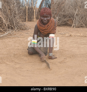 Les Nyangatom (Bumi) femme raclant le sol avec une machette, vallée de la rivière Omo, en Ethiopie du sud Banque D'Images