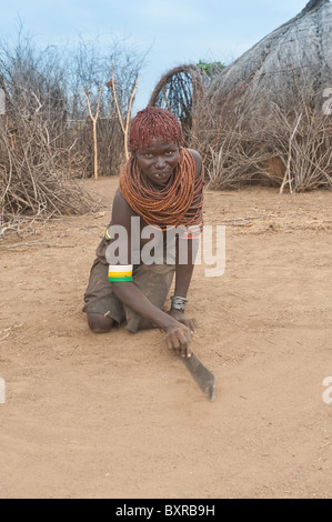 Les Nyangatom (Bumi) femme raclant le sol avec une machette, vallée de la rivière Omo, en Ethiopie du sud Banque D'Images